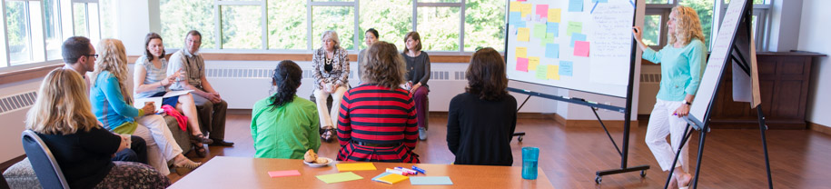 A group of instructors sitting in a group focused on a whiteboard activity