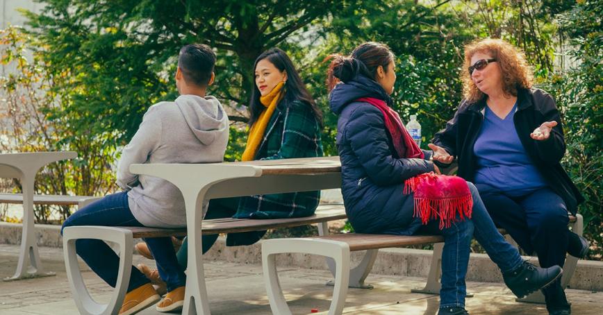 Four people sitting at a picnic table talking