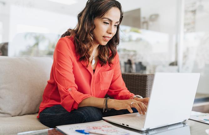 woman sitting on a couch typing on a computer