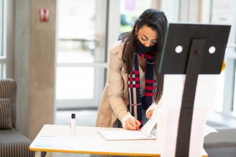 Person signing into work with a mask on Person-signing-in-wearing-a-mask