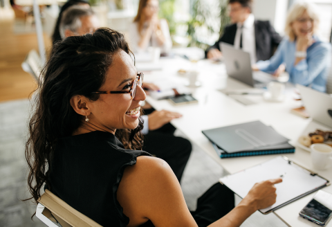 Person smiling with group at board table Person-smiling-with-group-at-board-table