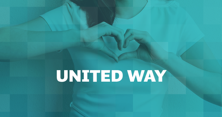 Person standing with their hands shaped into a heart in front of their chest.