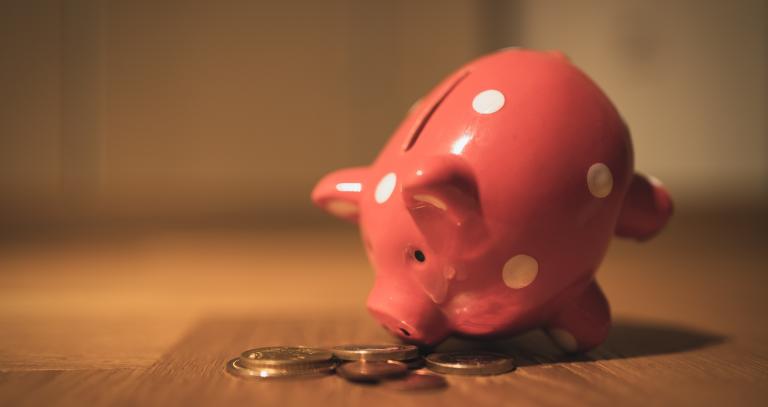 Pink piggybank and two coins on a table